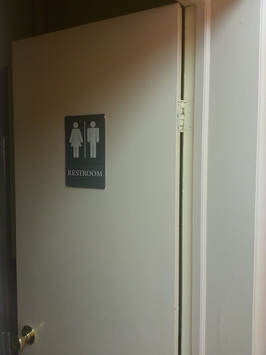 Restroom door with unisex sign and brass knob