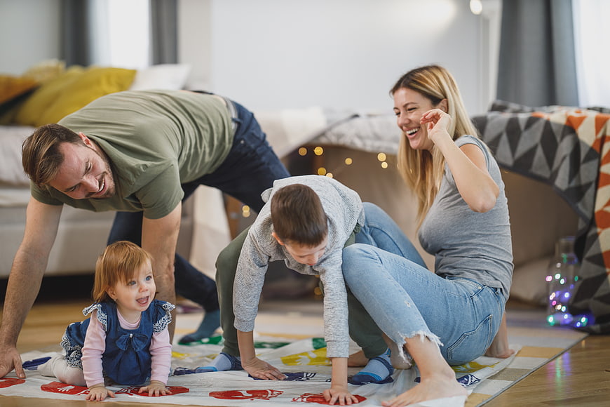 Happy family playing Twister game on living room floor