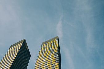 Low angle view of modern yellow skyscrapers against blue sky