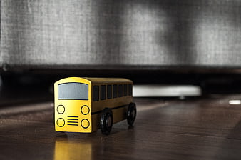 Yellow wooden toy school bus on dark wood surface