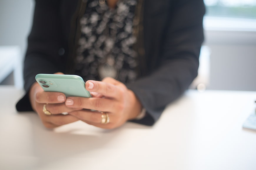 Close-up of woman's hands using smartphone at office desk