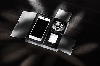 White Smartphone Unboxing with Accessories on Dark Wood