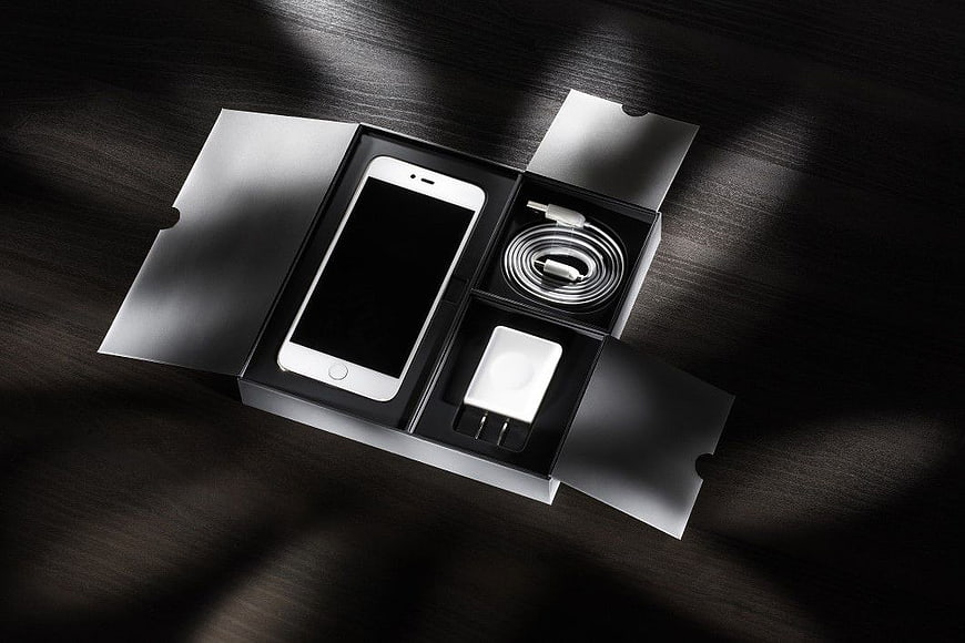 White Smartphone Unboxing with Accessories on Dark Wood
