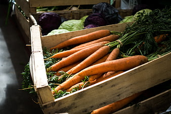 Fresh organic carrots in wooden crate at farmers market
