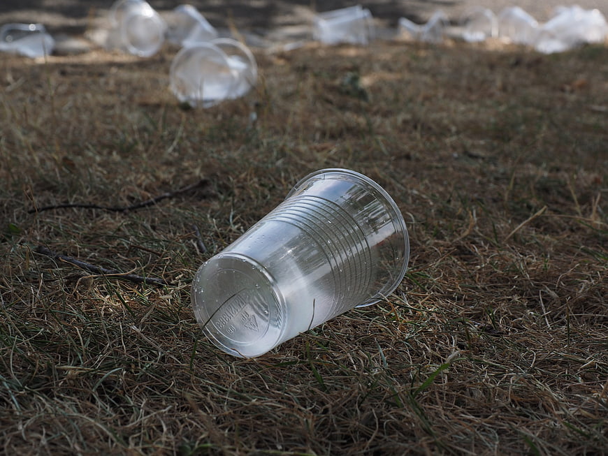 Plastic cup waste on dry grass environmental pollution
