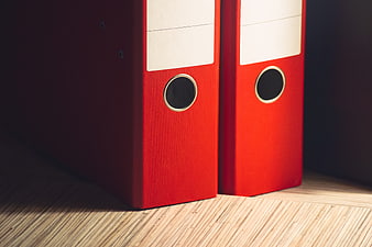 Close-up of red ring binders on a wooden shelf