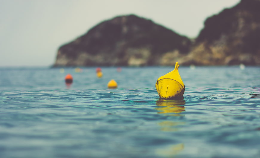 Yellow buoy floating in calm blue sea water