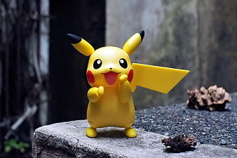 Cute Pikachu toy figure standing on a stone ledge outdoors