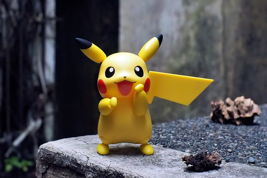 Cute Pikachu toy figure standing on a stone ledge outdoors