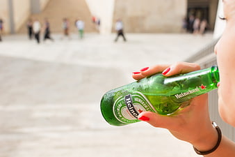 Woman drinking Heineken beer bottle outdoors