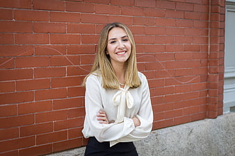 Smiling businesswoman in white blouse against red brick wall