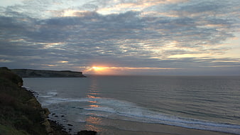 Dramatic Sunset Over Cliffs and Ocean with Cloudy Sky