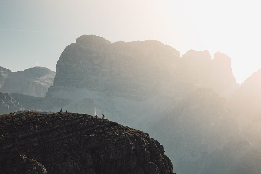 Hikers on Rocky Mountain Ridge with Sunlit Peaks