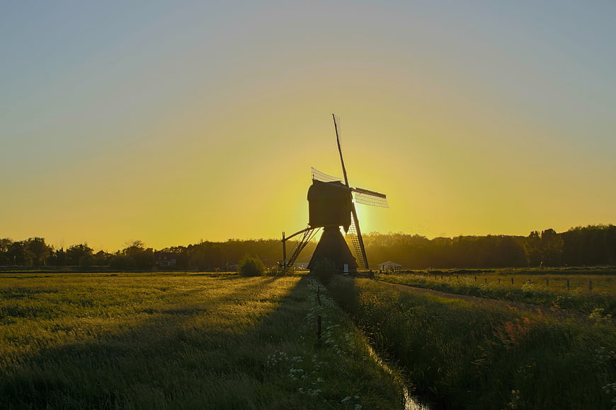 Silhouette of traditional Dutch windmill at golden hour sunset