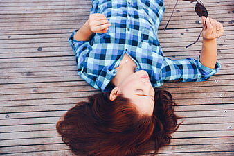 Relaxed woman lying on wooden deck with sunglasses
