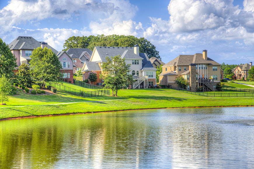 Suburban Lakefront Homes With Lush Green Lawns And Blue Sky