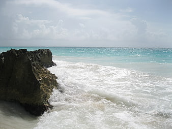 Turquoise Ocean Waves Crashing Against Dark Rocky Shore
