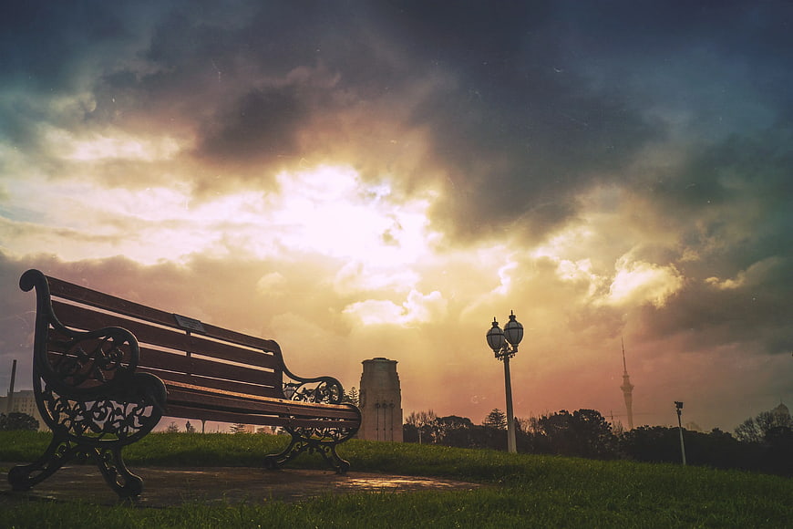 Empty Park Bench Silhouette Against Dramatic Sunset Sky