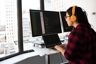 Female Programmer Coding on Laptop and Monitors in Office