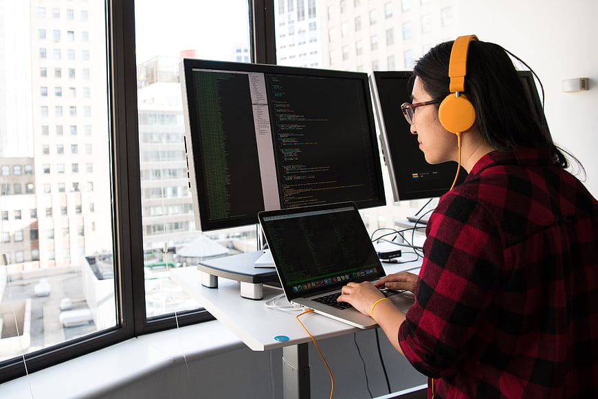 Female Programmer Coding on Laptop and Monitors in Office