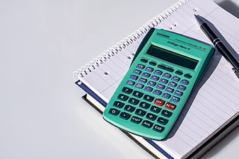 Green scientific calculator on notebook with pen