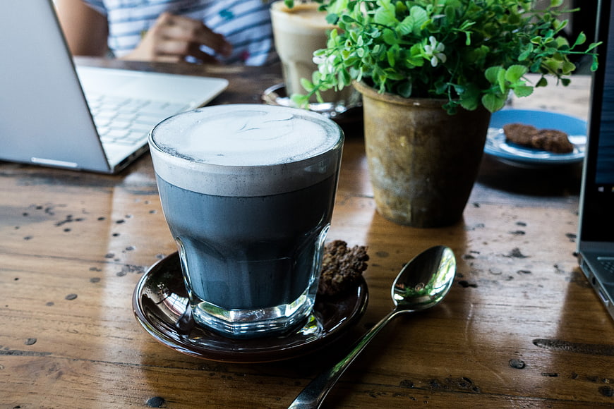 Black Charcoal Cappuccino on Wooden Cafe Table