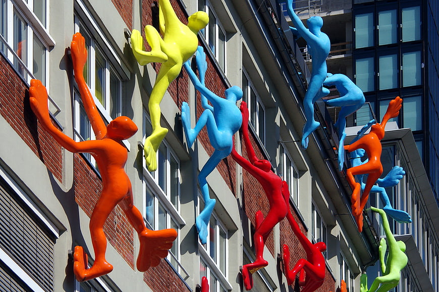 Colorful climbing figures on urban building facade