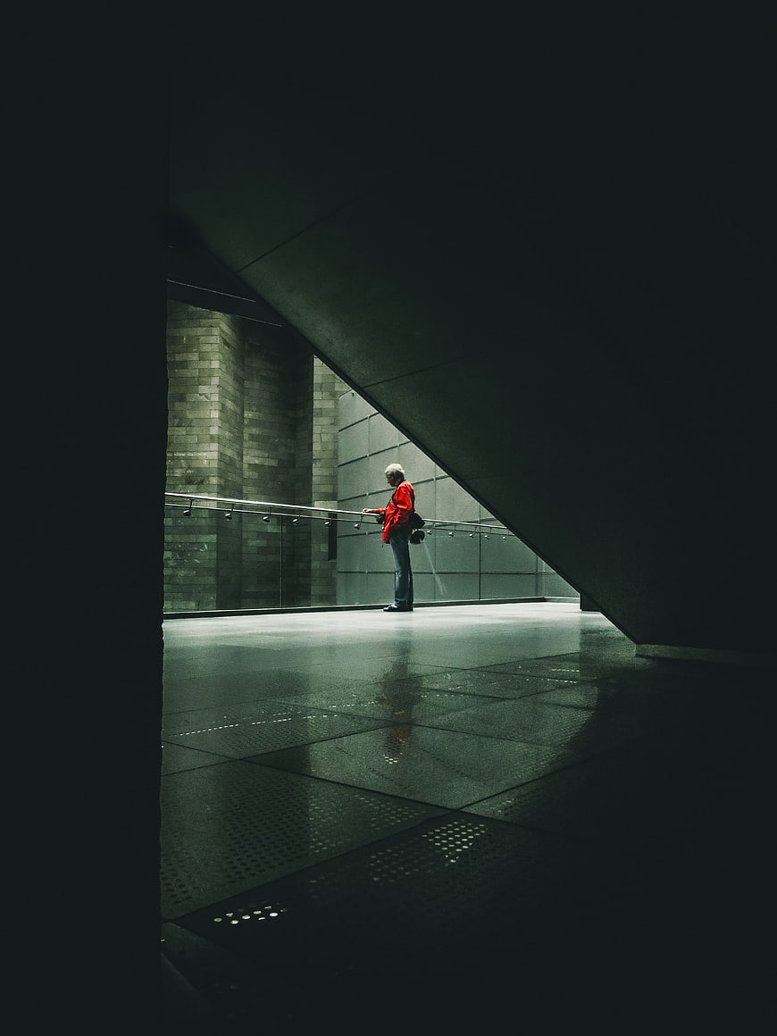 Senior man in red jacket standing in modern architectural space