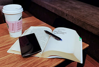 Open finance book with smartphone and coffee on wooden table