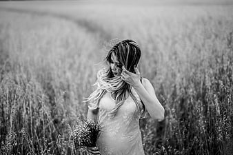 Pregnant woman in field holding baby's breath bouquet