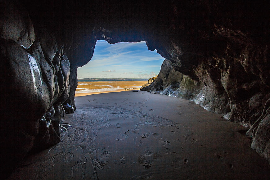 View from inside a sea cave looking out to a sandy beach