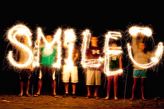 Group of people creating the word smile with sparklers at night