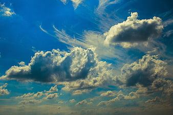 Dramatic white cumulus clouds against deep blue sky