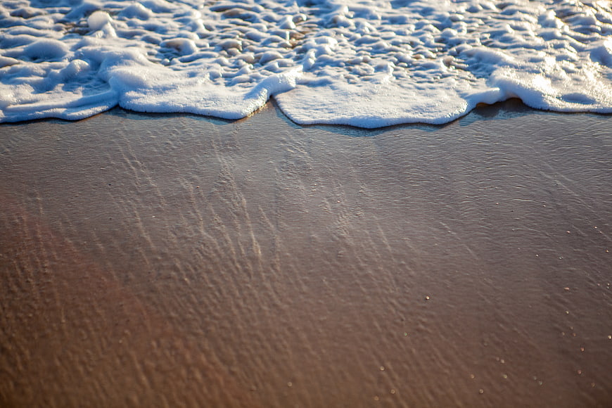 Foamy Ocean Waves Washing Over Wet Sandy Beach Shore