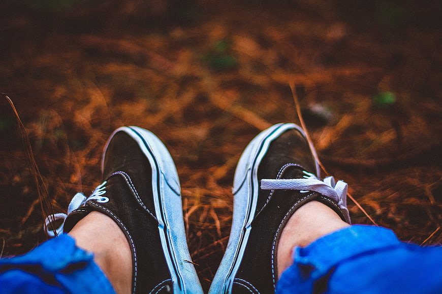First-person view of black sneakers on autumn ground