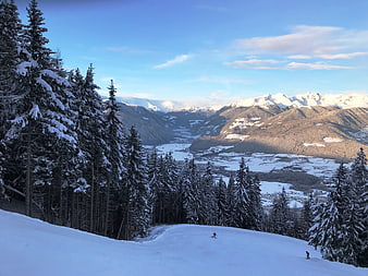 Skiers on snowy slope with mountain valley view