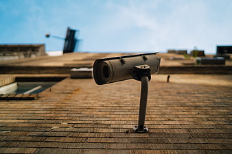 Weathered Security Camera On Rooftop With Blurred Urban Background