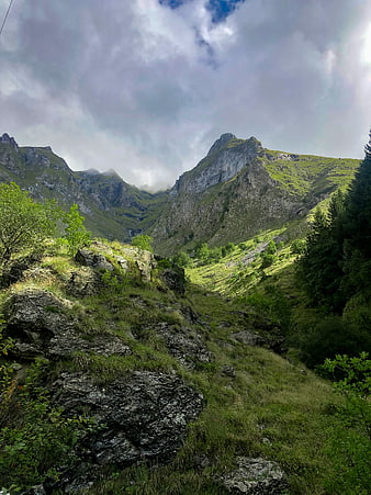 Dramatic Green Mountain Valley with Rocky Terrain and Cloudy Sky