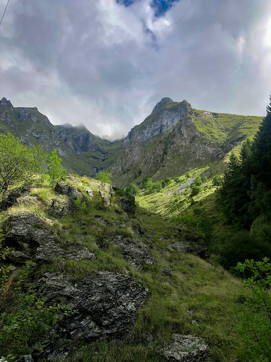 Dramatic Green Mountain Valley with Rocky Terrain and Cloudy Sky