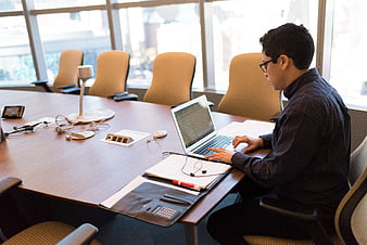 Man coding on laptop in modern conference room