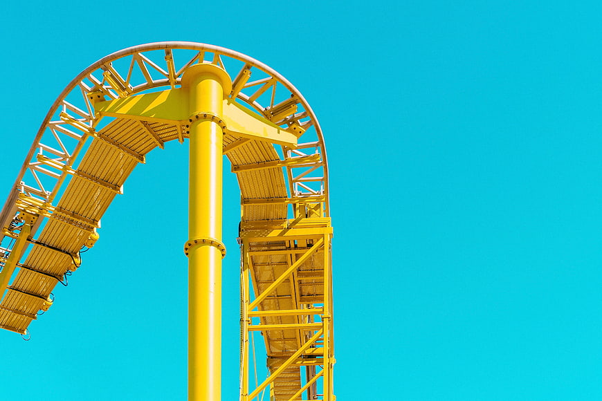 Yellow Roller Coaster Loop Against Blue Sky