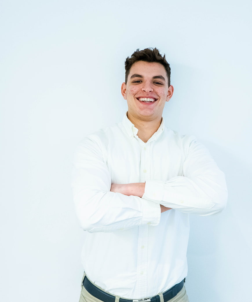 Smiling young man in white shirt with arms crossed