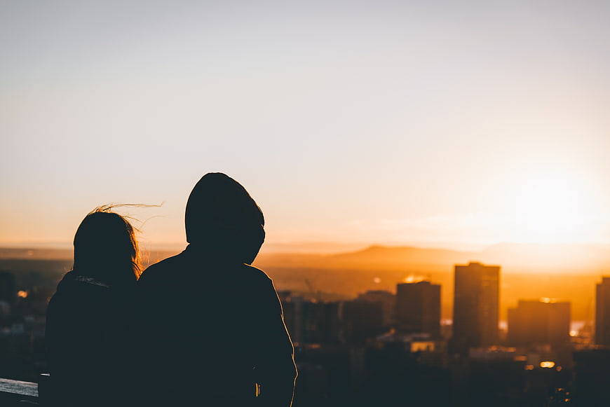 Silhouette of couple watching sunset over city skyline