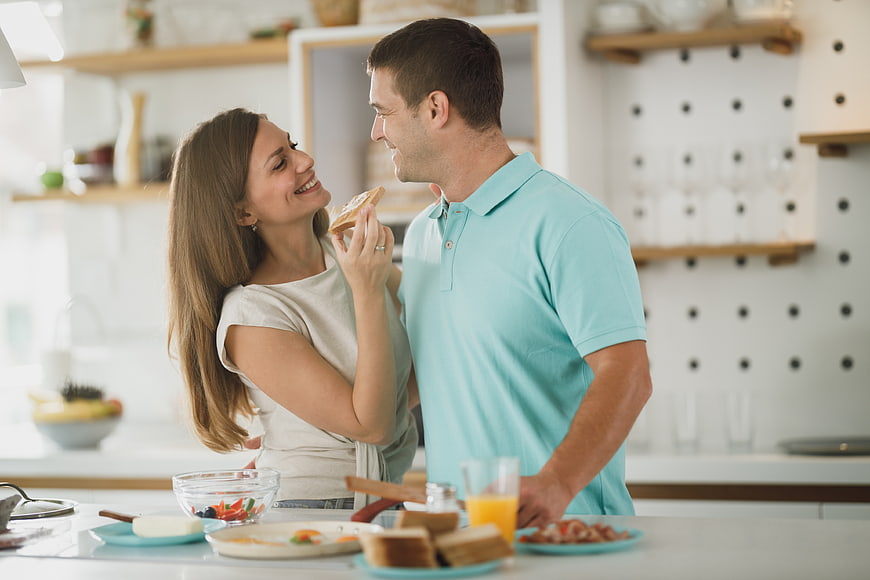 Happy couple sharing breakfast toast in modern kitchen