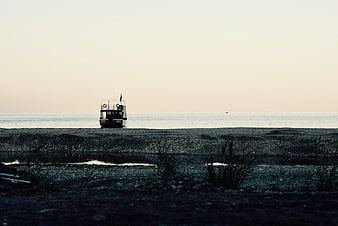 Lone boat stranded on pebble beach at dusk