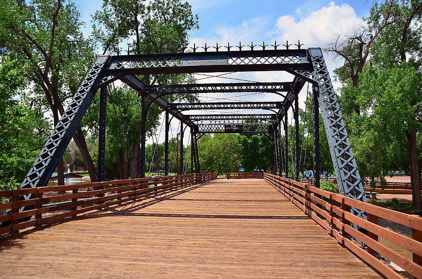 Wooden pedestrian bridge with metal truss in green park