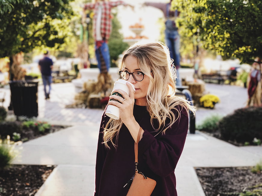 Blonde woman drinking coffee in autumn park