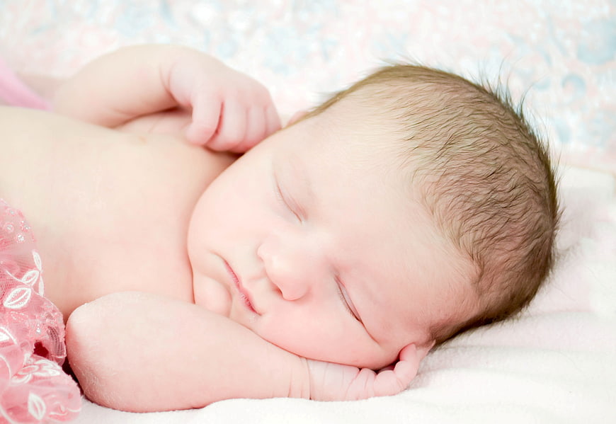 Sleeping newborn baby girl on pink blanket