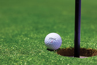 Golf ball resting on green near hole