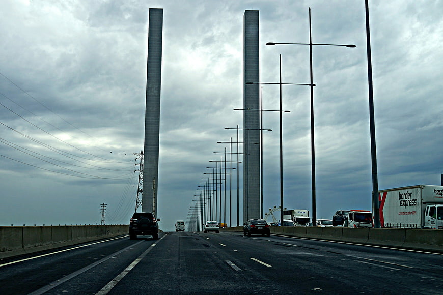 Highway traffic on a large suspension bridge under cloudy sky